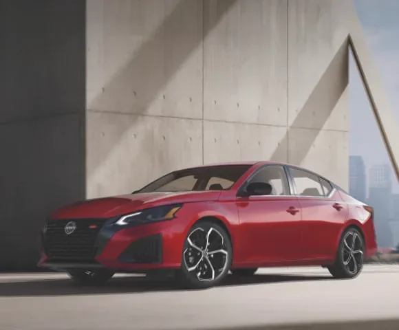 Red 2027 Nissan Altima midsize AWD sedan 3/4 profile view, parked in a well-lit garage at Dublin Nissan in Dublin GA