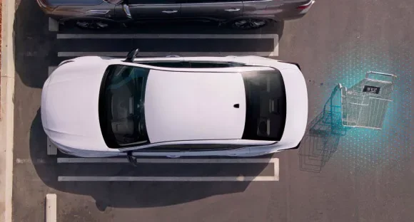 Top view of a white 2027 Nissan Altima in a parking lot with rear sensors detecting a shopping cart behind it at Dublin Nissan in Dublin GA