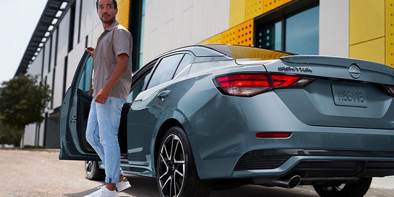 A person closing the door of a 2025 Nissan Sentra